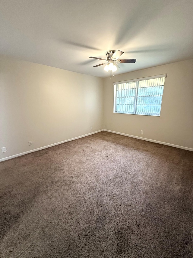 empty room featuring ceiling fan and dark carpet