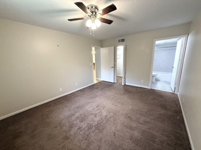 unfurnished bedroom featuring ceiling fan, ensuite bathroom, and dark carpet