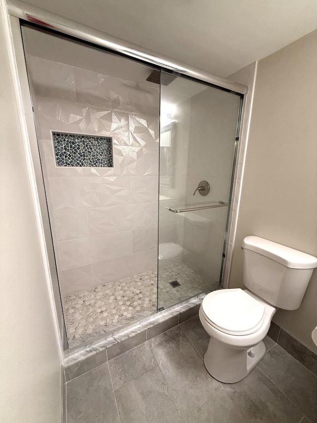 bathroom featuring toilet and a shower with shower door