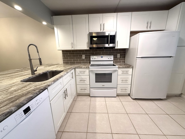 kitchen with sink, white appliances, white cabinetry, tasteful backsplash, and light stone countertops