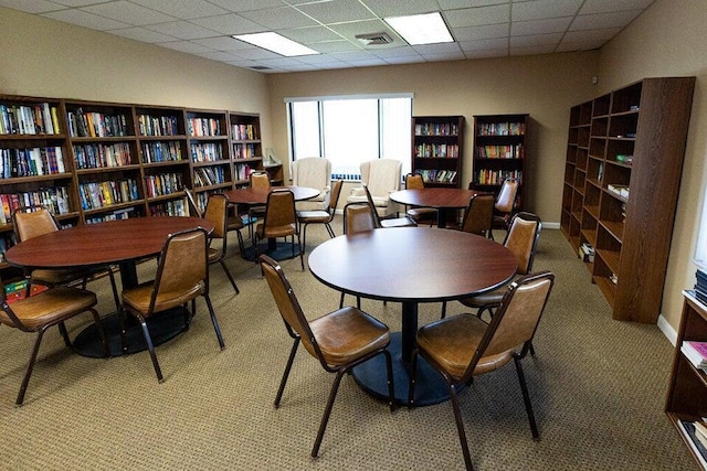 carpeted dining space featuring a paneled ceiling