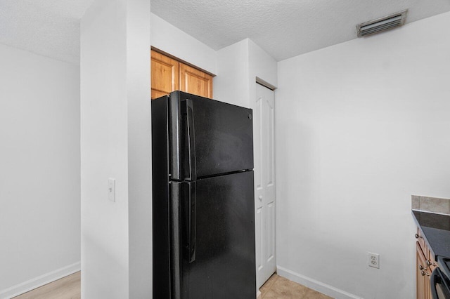 kitchen featuring black fridge and a textured ceiling