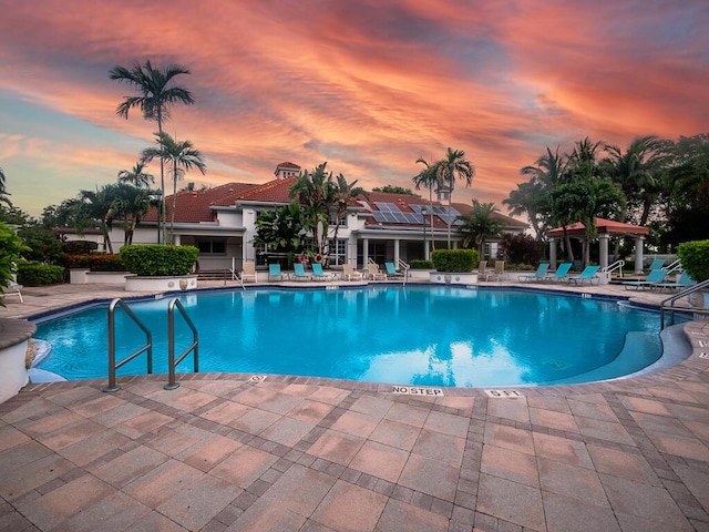 pool at dusk featuring a patio area