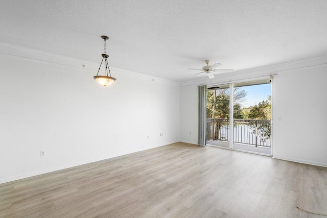 spare room with a textured ceiling, ceiling fan, light wood-type flooring, and crown molding