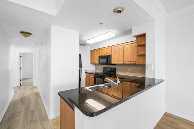 kitchen with black appliances, kitchen peninsula, sink, and a textured ceiling