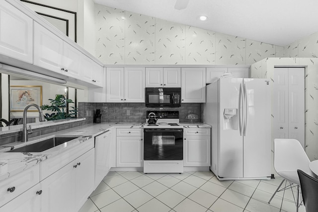 kitchen featuring light stone countertops, white appliances, sink, white cabinets, and light tile patterned flooring