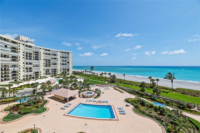 view of swimming pool featuring a patio, a beach view, and a water view