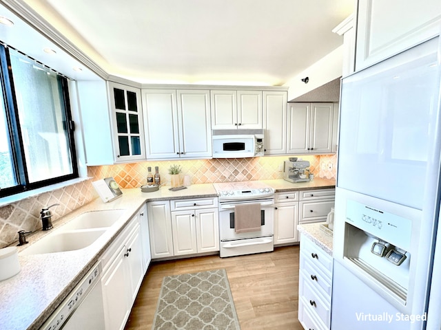 kitchen with sink, white appliances, white cabinetry, and light wood-type flooring