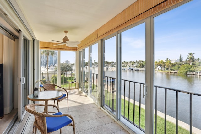 sunroom / solarium featuring ceiling fan and a water view