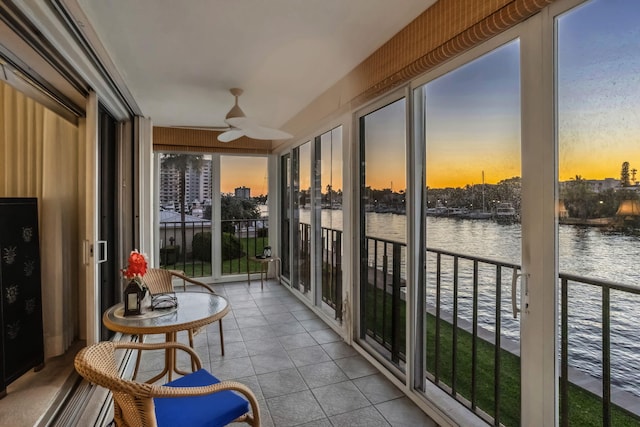 sunroom / solarium with ceiling fan and a water view