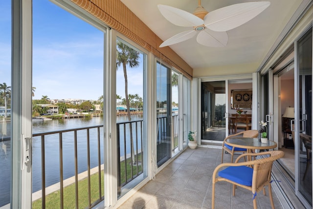 sunroom featuring a water view and ceiling fan