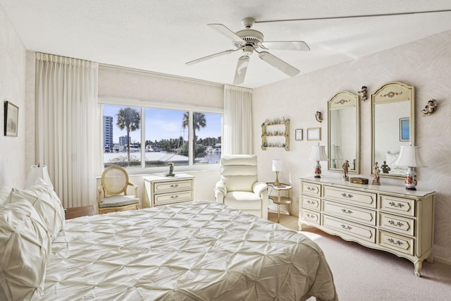 carpeted bedroom featuring ceiling fan and a textured ceiling