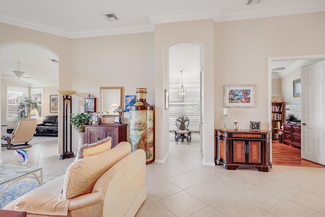 living room featuring ceiling fan with notable chandelier, light tile patterned flooring, and ornamental molding