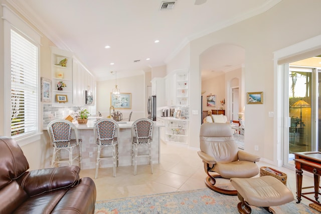 living room with light tile patterned floors, vaulted ceiling, built in shelves, and crown molding