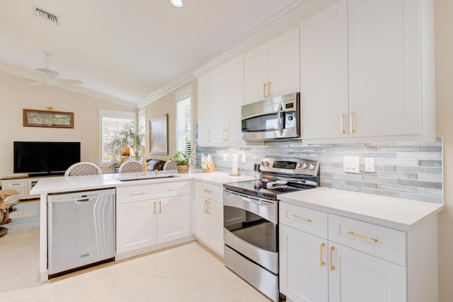 kitchen featuring kitchen peninsula, stainless steel appliances, vaulted ceiling, and white cabinetry