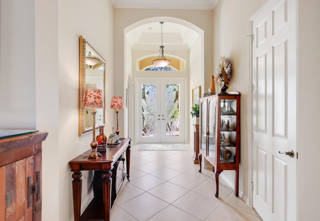 foyer entrance with light tile patterned flooring, crown molding, a high ceiling, and french doors