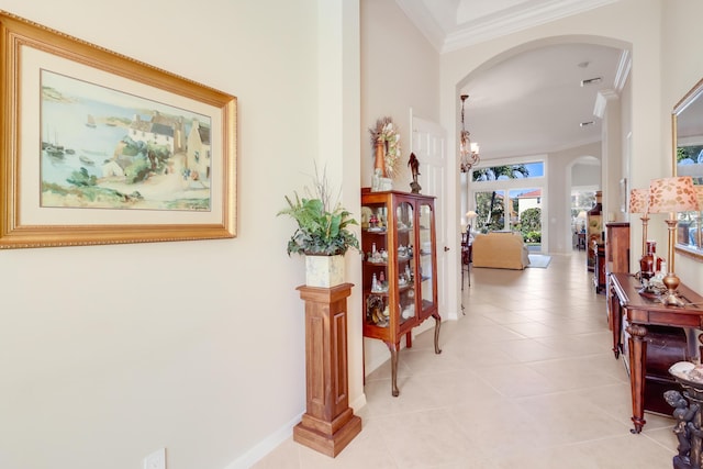 hall featuring crown molding, light tile patterned floors, and an inviting chandelier