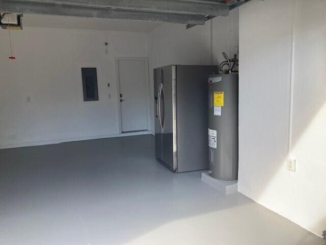 garage with a garage door opener, stainless steel fridge, electric water heater, and electric panel