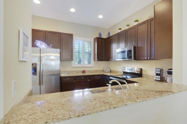 kitchen featuring a peninsula, appliances with stainless steel finishes, a sink, and recessed lighting