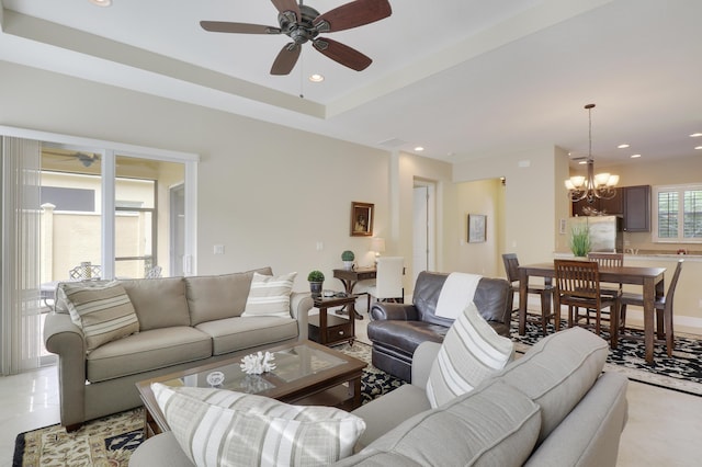 living area featuring ceiling fan with notable chandelier, a tray ceiling, and recessed lighting