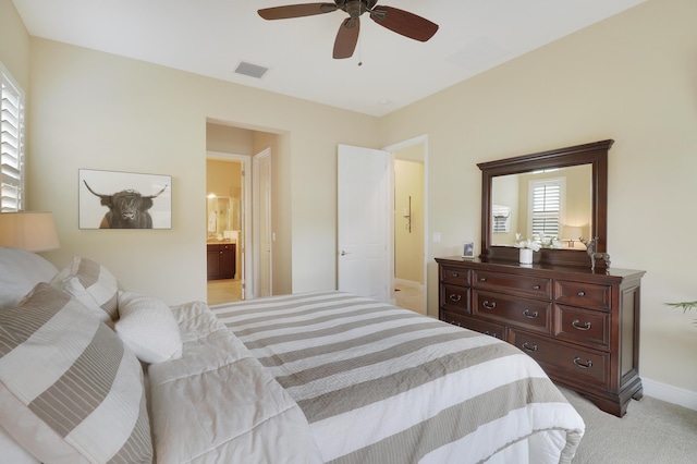 carpeted bedroom with ensuite bath and ceiling fan