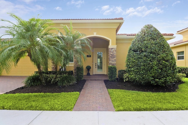 property entrance featuring a tiled roof, a yard, and stucco siding