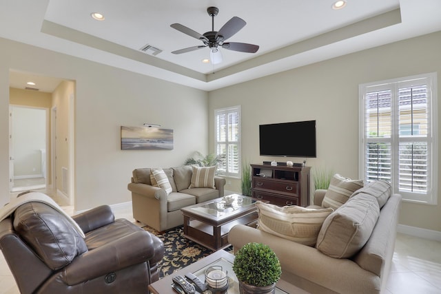 living room featuring a ceiling fan, a raised ceiling, and baseboards