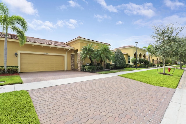 view of front facade featuring an attached garage, a tiled roof, decorative driveway, stucco siding, and a front lawn