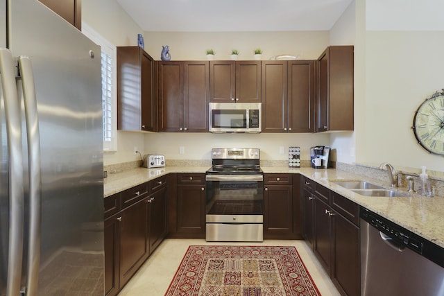 kitchen with a wealth of natural light, light stone counters, stainless steel appliances, and a sink