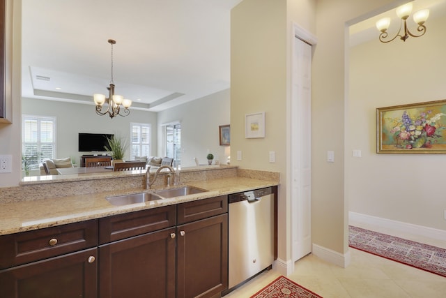 kitchen featuring light stone counters, an inviting chandelier, a tray ceiling, stainless steel dishwasher, and a sink