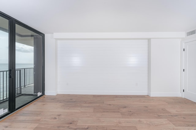 spare room featuring expansive windows and light hardwood / wood-style floors