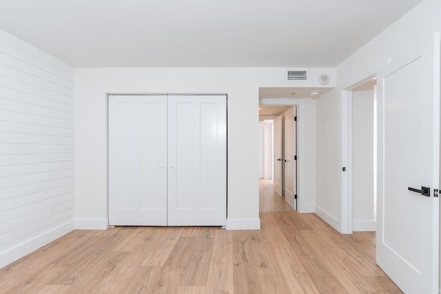 unfurnished bedroom with a closet and light wood-type flooring