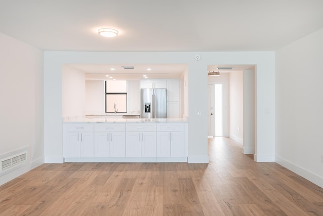 kitchen with stainless steel fridge with ice dispenser, light hardwood / wood-style floors, white cabinetry, and sink