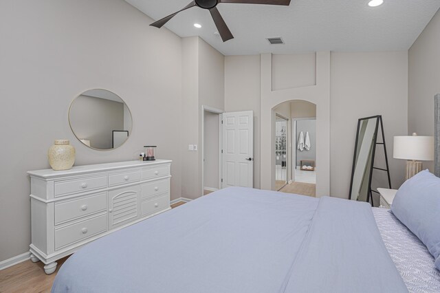 bedroom with ceiling fan, high vaulted ceiling, and light hardwood / wood-style flooring