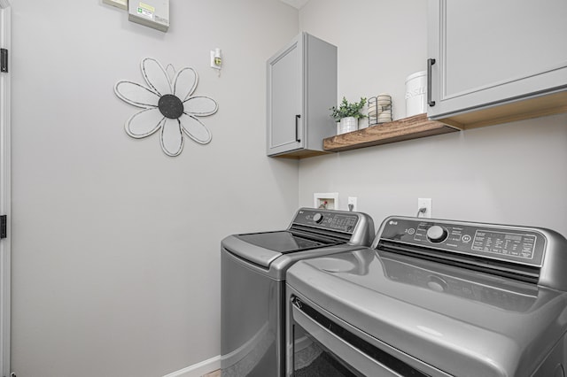 clothes washing area with cabinets and separate washer and dryer