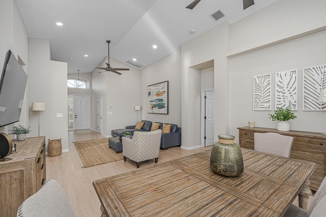 dining space with light hardwood / wood-style flooring and high vaulted ceiling