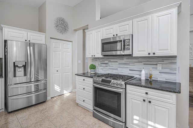 kitchen featuring dark stone countertops, white cabinets, stainless steel appliances, and light tile patterned floors