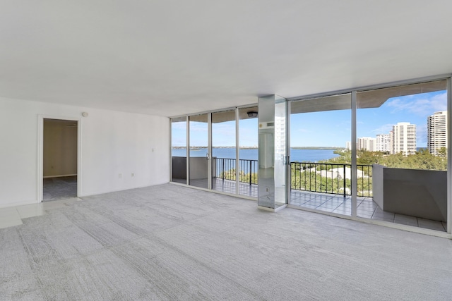 carpeted spare room featuring plenty of natural light, a water view, and floor to ceiling windows