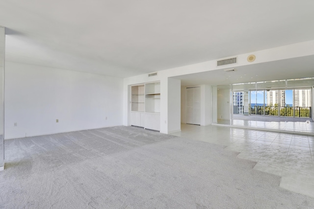 spare room with light carpet, visible vents, and built in features