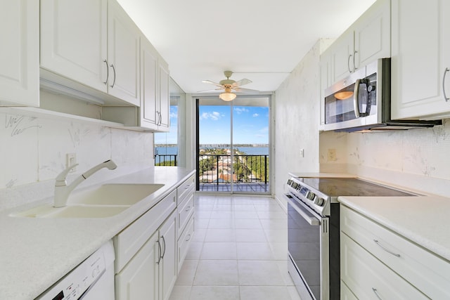 kitchen with floor to ceiling windows, tasteful backsplash, light countertops, appliances with stainless steel finishes, and a sink