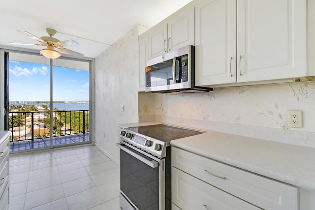 kitchen with stainless steel appliances, a ceiling fan, light countertops, and a wall of windows