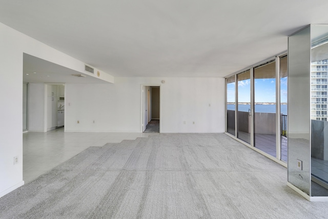 spare room featuring a water view, carpet, and visible vents