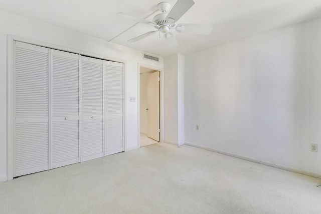 unfurnished bedroom featuring baseboards, visible vents, light colored carpet, ceiling fan, and a closet