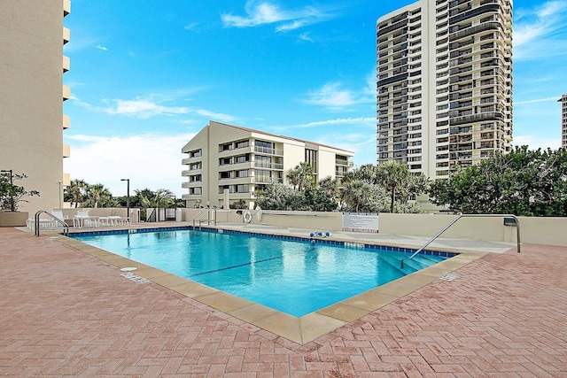 community pool with a patio area and fence