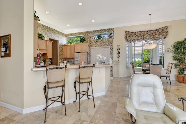 kitchen with white refrigerator with ice dispenser, hanging light fixtures, ornamental molding, a kitchen bar, and kitchen peninsula