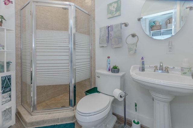 bathroom featuring sink, a shower with shower door, and toilet