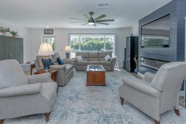 living room featuring ceiling fan and a fireplace