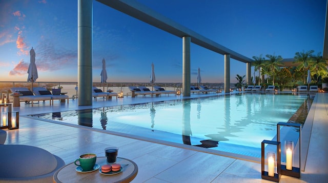 pool at dusk featuring a water view