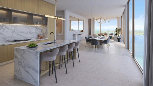 kitchen featuring sink, a wall of windows, plenty of natural light, an island with sink, and a water view