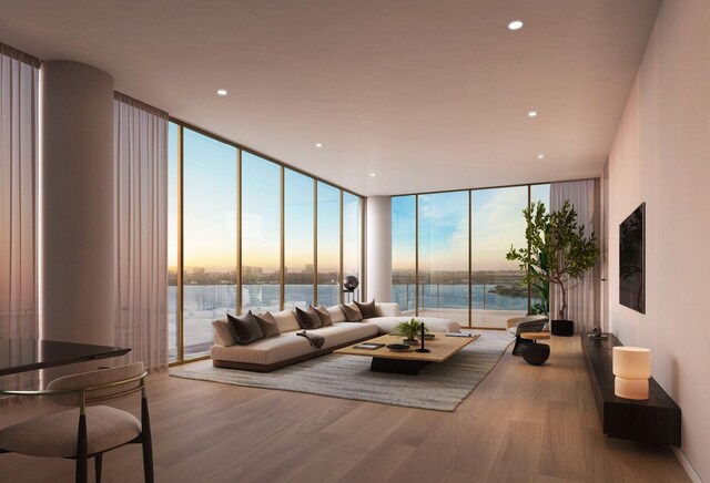 living room with wood-type flooring, a water view, plenty of natural light, and floor to ceiling windows